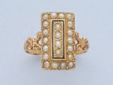 une image représentant une bague en or ornée de perles et d'une pierre noire