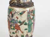 a vase with a painting on it sitting on a table