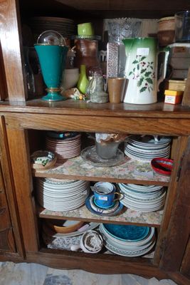 une armoire en bois sur laquelle sont posées de nombreuses assiettes et tasses