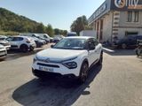 La voiture blanche est garée devant un immeuble devant lequel sont garées d'autres voitures.