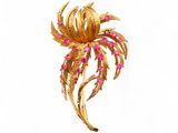 un gros plan sur une broche en or ornée de pierres roses