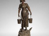 a bronze figure of a woman with buckets on a pedestal