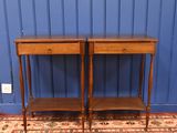 pair of antique side tables on a rug in front of a blue wall