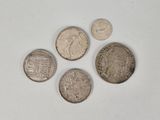 four different types of silver coins on a white surface