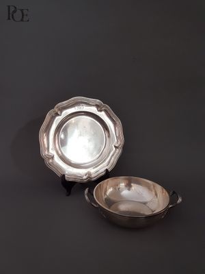une assiette en argent et un bol en argent posés sur un fond noir