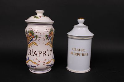 pair of white and gold decorated jars with black writing on them