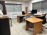 a room with a desk, chair, and a fan in it