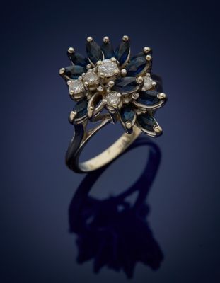 a gold ring with blue and white diamonds on a dark background