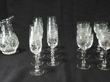 six verres à vin en cristal et un pichet sur fond noir