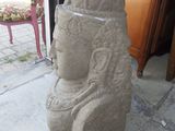 a stone statue of a woman sitting on the sidewalk