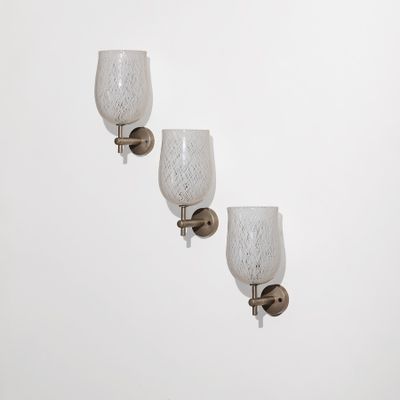 trois appliques murales en verre sur un mur blanc, devant un fond blanc
