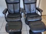 une paire de fauteuils inclinables en cuir noir, avec repose-pieds et pouf assortis