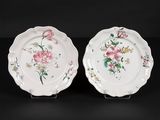 two white plates with pink flowers on them on a black surface