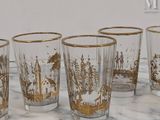 four glasses with gold designs on them sitting on a marble surface
