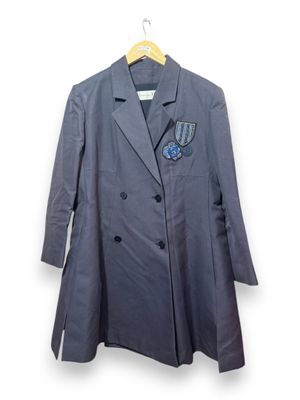 un manteau gris à revers bleu, suspendu à un cintre sur un mur blanc