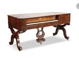 an old piano sitting on top of a wooden table