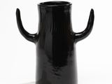 a black vase with a black handle sitting on a white surface