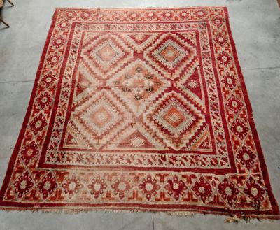 un vieux tapis rouge et beige orné d'un motif en losanges