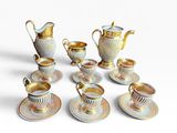 five cups and saucers and a teapot on the table