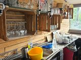 une cuisine équipée d'une cuisinière, d'un évier et d'étagères remplies de verrerie