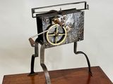 une image représentant une horloge en métal et en bois posée sur un socle en bois