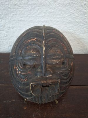 a wooden mask on a table with a white wall in the background