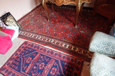 une pièce avec une table, une chaise, un tapis et d'autres objets posés par terre