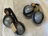 two pairs of goggles sitting on a bed