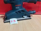 La ponceuse orbitale Bosch est posée sur une table, à côté d'une boîte rouge