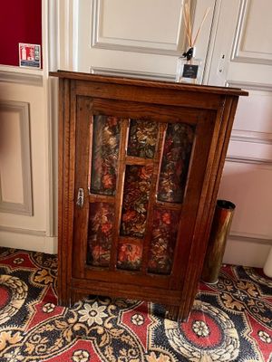 a wooden cabinet with a glass door in the corner of a room