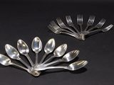 Plusieurs cuillères et fourchettes en argent sont disposées dans une composition florale