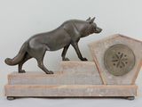 statue of a dog on a stone base with a clock in the background