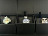 trois montres sont posées dans une boîte noire sur une table