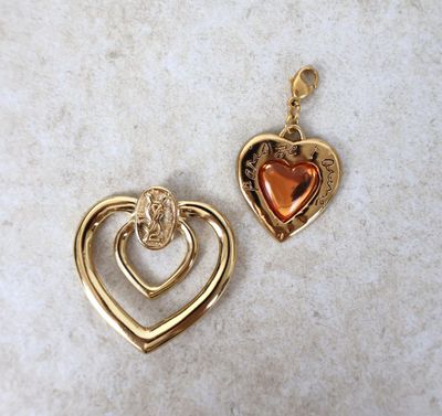 deux pendentifs en forme de cœur en or posés sur une surface en marbre
