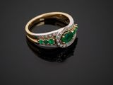 an emerald and diamond ring on a black surface