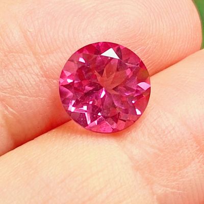 a close up of a person holding a pink diamond in their hand