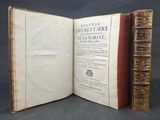 an open book with two books on top of it on a table