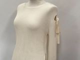 a white sweater on a mannequin stand against a white wall
