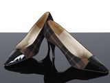 une paire d'escarpins à carreaux noirs et marron posés sur une surface noire