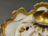a close up of a gold and white vase on a table