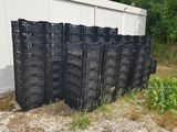 de nombreuses caisses en plastique noir empilées les unes sur les autres devant un bâtiment