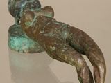 statue of a person laying down on a table with a reflection on the surface