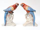 two figurines of parrots sitting on a tree branch