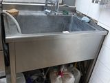 a sink in a kitchen with a lot of clutter on the floor
