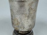 an old silver cup with a metal base on a white surface