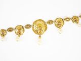 un gros plan d'un collier en or orné de perles sur fond blanc