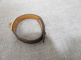 a close up of a brown leather bracelet on a gray surface