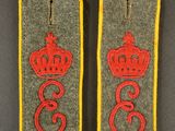 deux insignes militaires ornés d'une couronne, posés sur un fond gris
