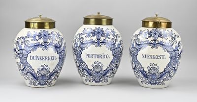 trois vases bleus et blancs avec des couvercles dorés sur fond gris