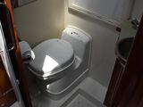 a white toilet sitting in a small bathroom next to a window
